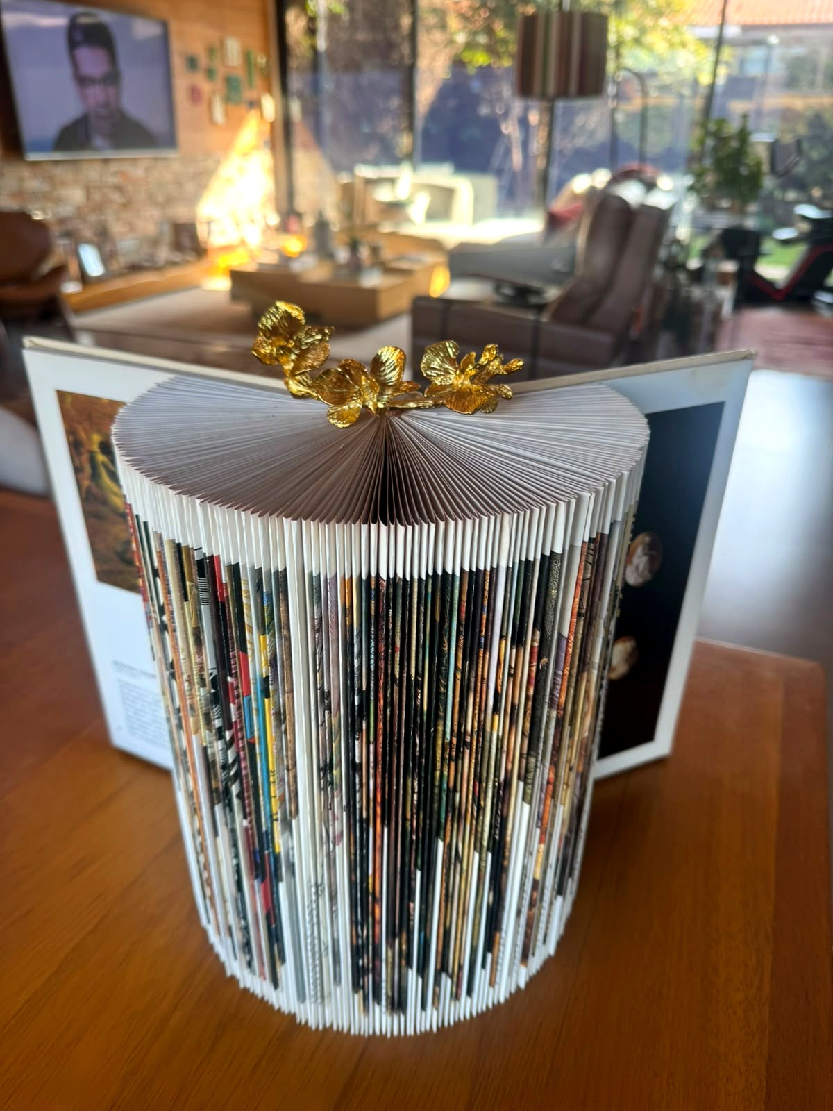 Vaso feito de revista dobrada com flores douradas, criado por aluna