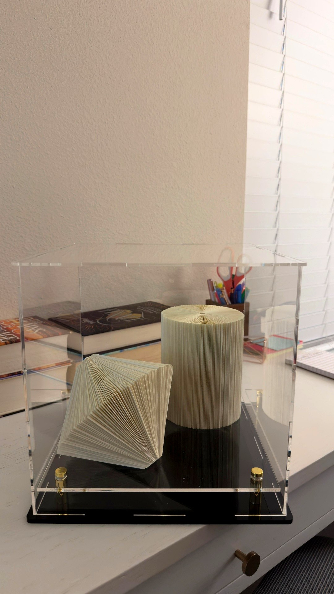 Esculturas de livro exibidas em cúpula de acrílico, feitas por aluna